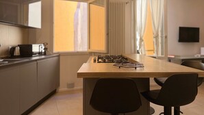 A modern kitchen with a central island, a built-in stove, and a dining area with two chairs. - Casa Accademia in the Heart of Bologna (Bologna)