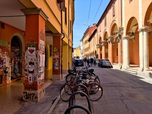A narrow street with parked bicycles, a building with columns, and a clear sky. - Casa Accademia in the Heart of Bologna (Bologna)