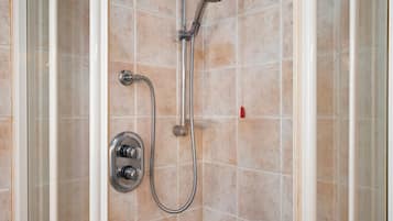 Eine Dusche mit einer verstellbaren Duschbrause und einer fest installierten Duschbrause, beide an einer gefliesten Wand befestigt.