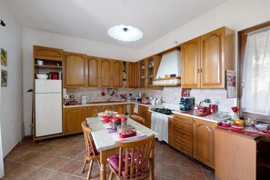 A kitchen with wooden cabinets, a dining table with chairs, a refrigerator, and various kitchen appliances. - Double Room with Shared Terrace, Lake View and Wi-Fi (Oschiri)