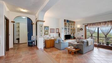 Uma sala de estar ampla com lareira, televisão e estante de livros.