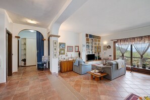 Un salón espacioso con chimenea, televisor y estantería.