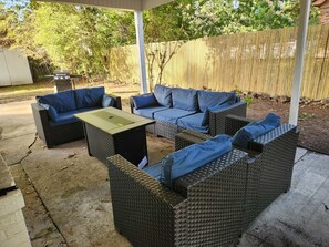An outdoor patio with wicker furniture, a table, and a grill.