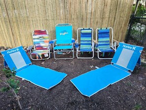 Four blue lounge chairs with 'Hurley' branding, positioned in front of a bamboo fence.