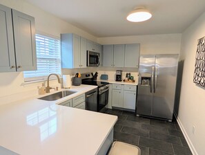 Une cuisine moderne avec des armoires blanches, des appareils en acier inoxydable et un grand îlot central.