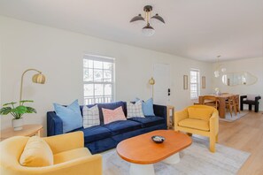 A living room with a sofa, armchairs, a coffee table, and a dining area with a table and chairs.