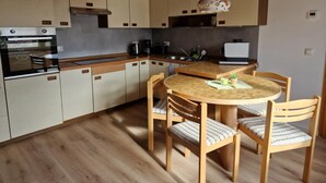 A kitchen with wooden cabinets, a round dining table, and chairs. - NEW! Vacation apartment Zapfe Schnabelwaid (Schnabelwaid)