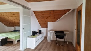 A room with a sloped ceiling, a bed, a desk with a chair, and a white dresser. - NEW! Vacation apartment Zapfe Schnabelwaid (Schnabelwaid)