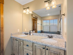 A bathroom with two sinks, wooden cabinets, a mirror, and a window with blinds. - Mins to Park City & Deer Valley! 4BR Townhome (Hideout)