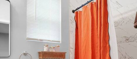 A bathroom with a white toilet, a wooden shelf, a towel ring, and a shower curtain.