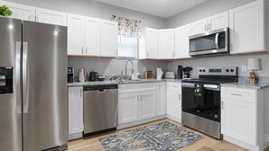 A modern kitchen with stainless steel appliances, white cabinetry, and a patterned rug. - Luxe Downtown Townhome-Sleeps 6 Brand New Build! (Indianapolis)