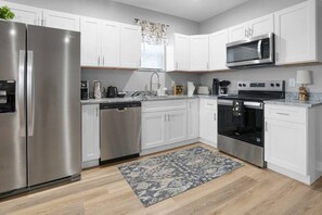 Una cocina moderna con electrodomésticos de acero inoxidable, armarios blancos y una alfombra estampada.