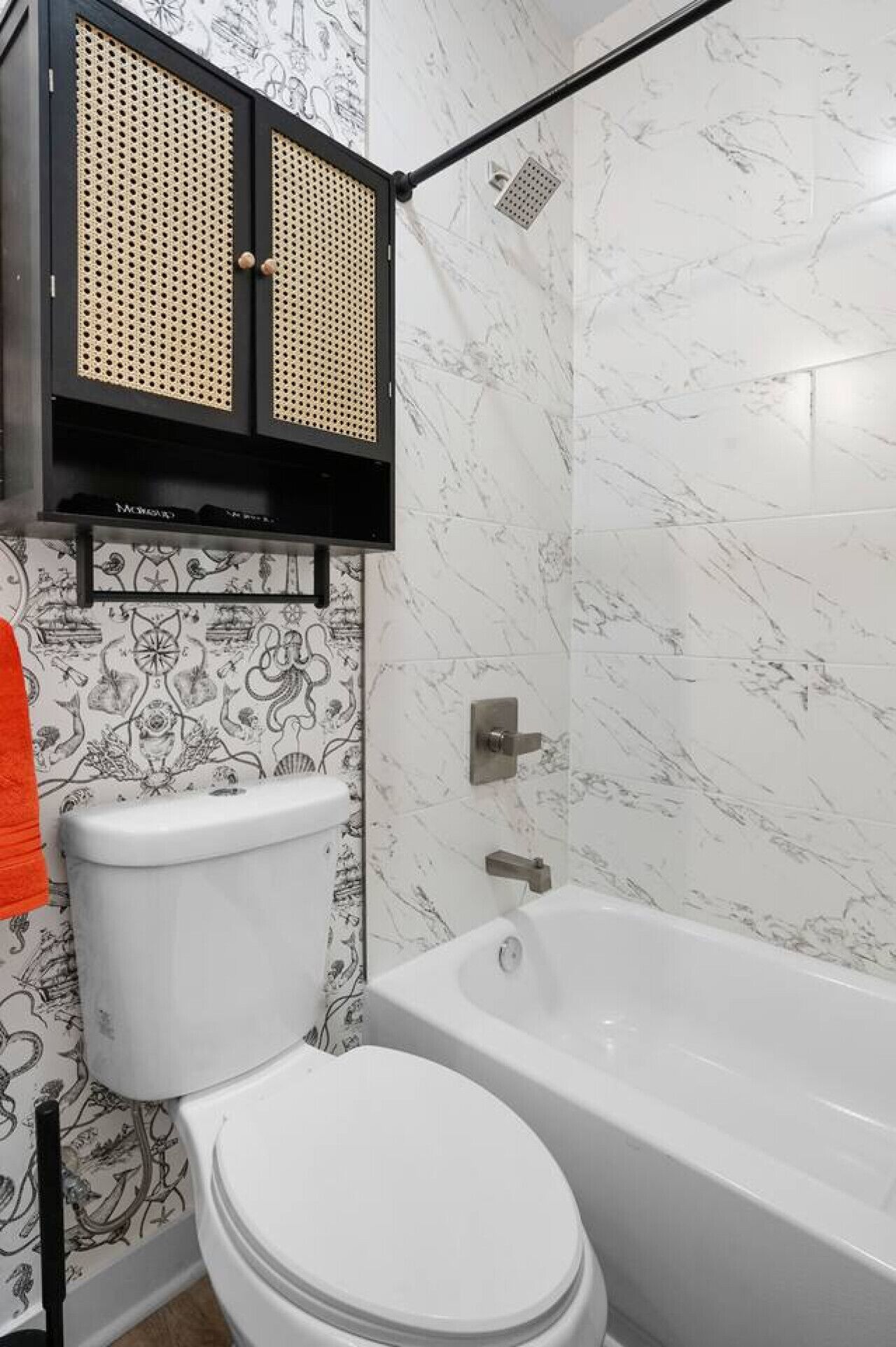 Et badeværelse med toilet, badekar og et sort skab med hullede paneler.