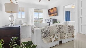 Ein Hotelzimmer mit einem Bett, einem Schreibtisch, einem Deckenventilator, einem Fernseher und Blick ins Freie.