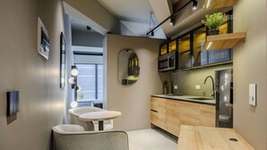 Een moderne keuken met een ronde spiegel, houten kastjes en een ingebouwde magnetron.
