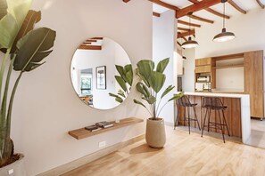 A modern kitchen with wooden cabinets, a round mirror, a potted plant, and a bar area with stools. - NOK Peaceful 3BR in Medellin (Medellín)