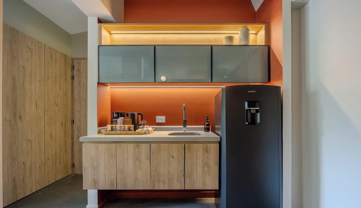 A modern kitchen with wooden cabinets, a black refrigerator, and a coffee maker.