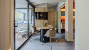 A modern interior with a round dining table, chairs, a flat-screen TV, and a sliding glass door leading to a balcony. - NOK Stylish 3BR Apartment w/ Terrace in Zona Rosa (Bogotá)