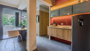 A modern kitchen with a built-in coffee machine, a sink, and a dining area with a chair. - NOK Stylish 3BR Apartment w/ Terrace in Zona Rosa (Bogotá)