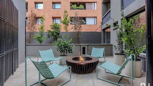 A rooftop patio with two green metal chairs, a central fire pit, and potted plants. - NOK Stylish 3BR Apartment w/ Terrace in Zona Rosa (Bogotá)