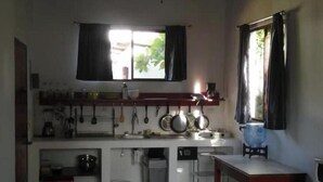 Eine kleine Küche mit Fenster, Spüle, Herd und Wasserspender.