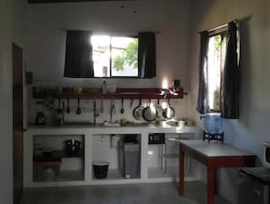 A compact kitchen with a window, a sink, a stove, and a water dispenser. - Cabañas Paolone Popoyo 1, air conditioning, pool (Tola)