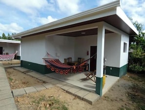 A single-story building with a covered patio area, a hammock, and a small table. - Cabañas Paolone Popoyo 1, air conditioning, pool (Tola)