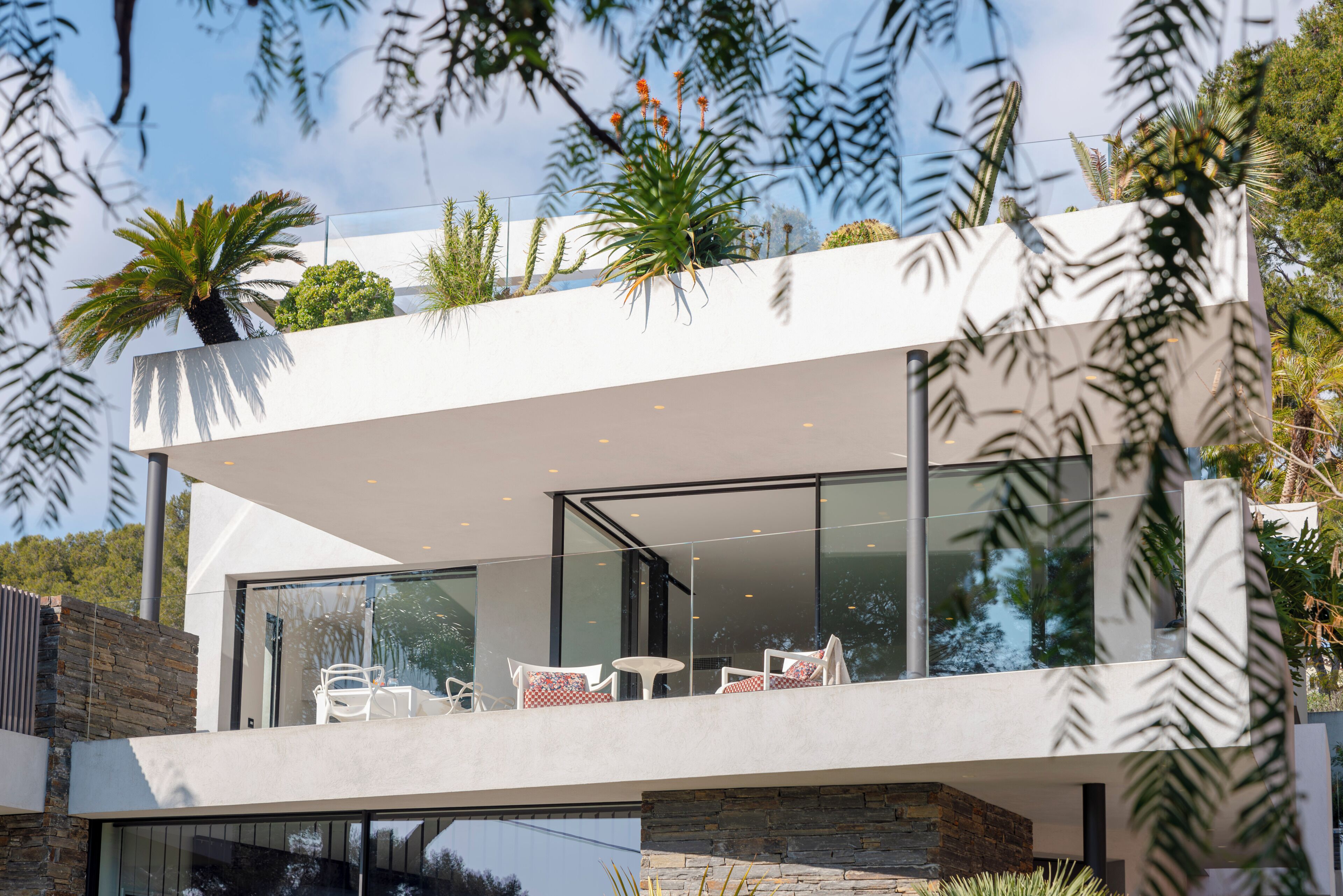 Une maison moderne dotée d’un balcon, de portes vitrées et de mobilier d’extérieur.