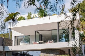 Ein modernes Haus mit Balkon, Glastüren und Gartenmöbeln.