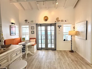 A room with a dining table, a sofa, a chair, a lamp, and a door leading outside. - Coastal Caribbean Cottage (St Thomas)