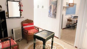 Ein Zimmer mit einem hölzernen Bett, einem kleinen Tisch, einer Heizung, einem Spiegel und einer Tür, die in einen anderen Raum führt.