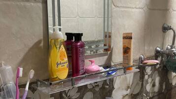 Une salle de bain avec un lavabo blanc, un miroir et une étagère contenant des articles de toilette.