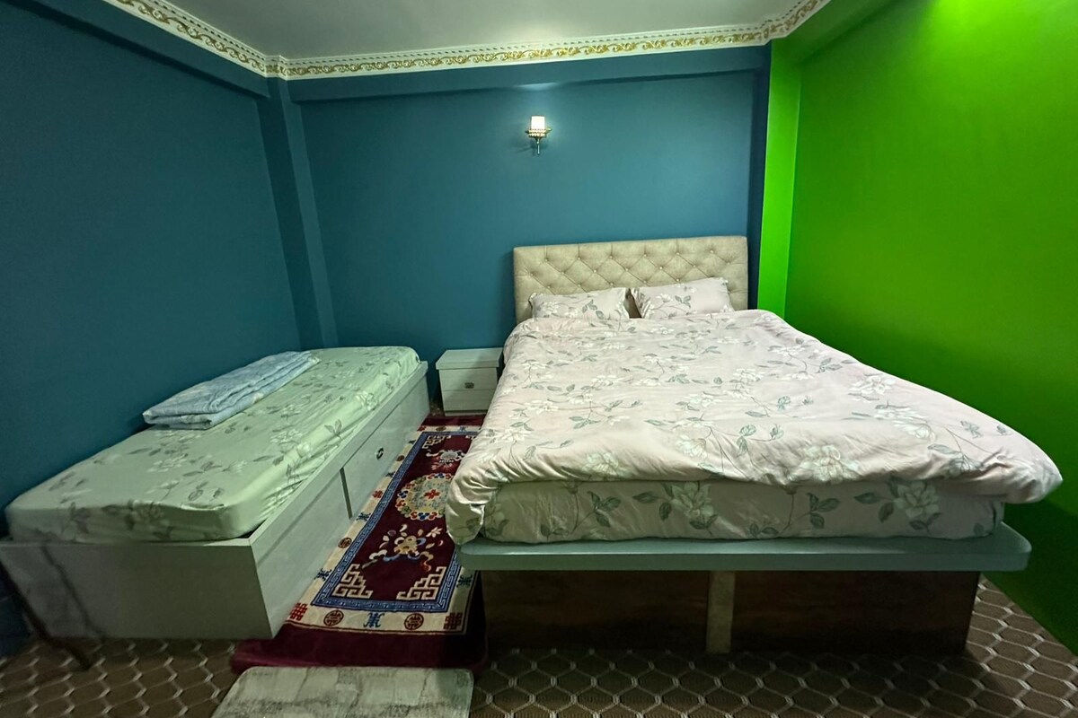 Quarto com cama, mesa de cabeceira e uma pequena mesa com um colchão.