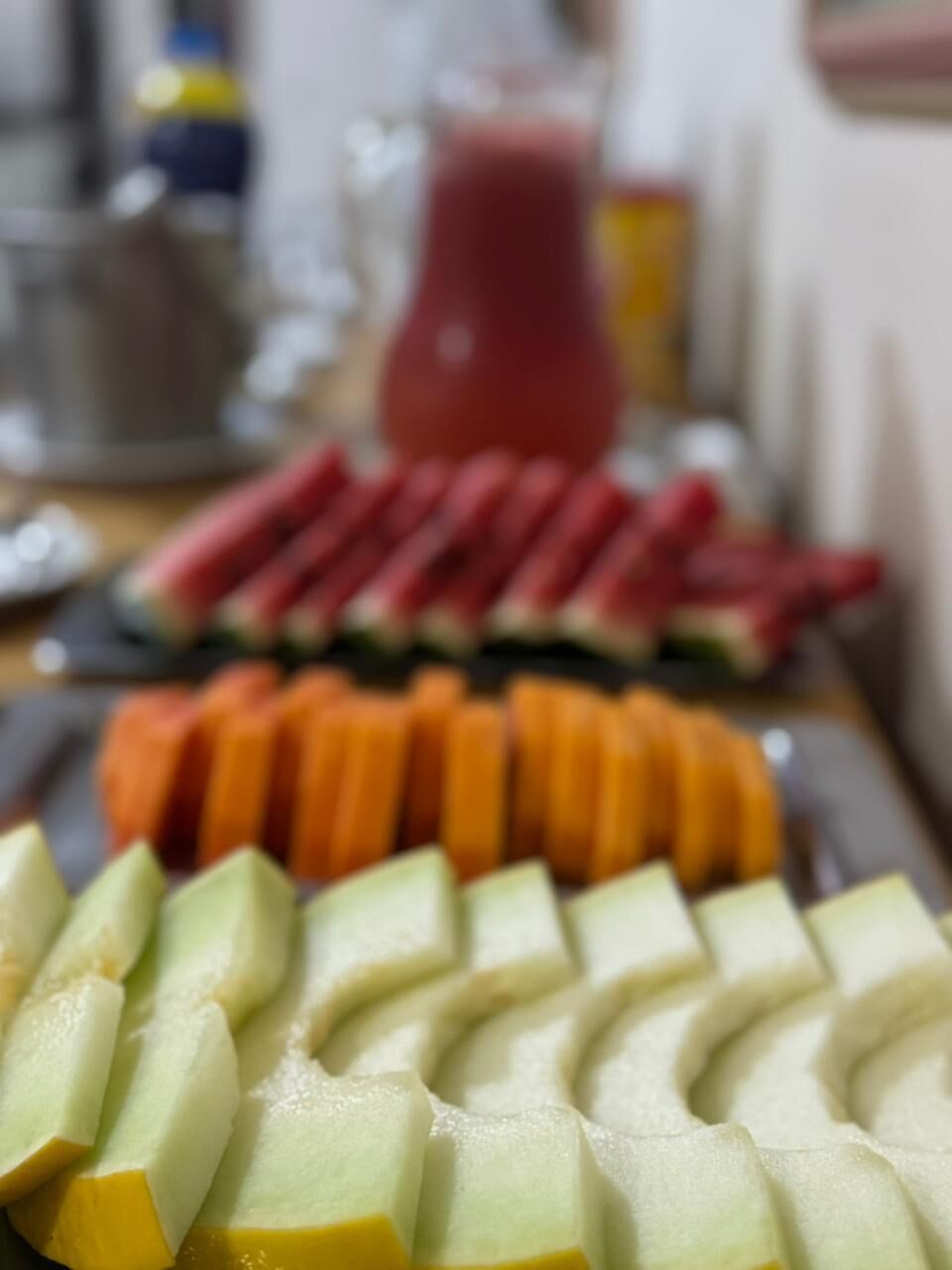 Une table avec des fruits coupés en tranches et un verre d’une boisson rouge.