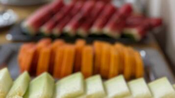 Une table avec des fruits coupés en tranches et un verre d’une boisson rouge.