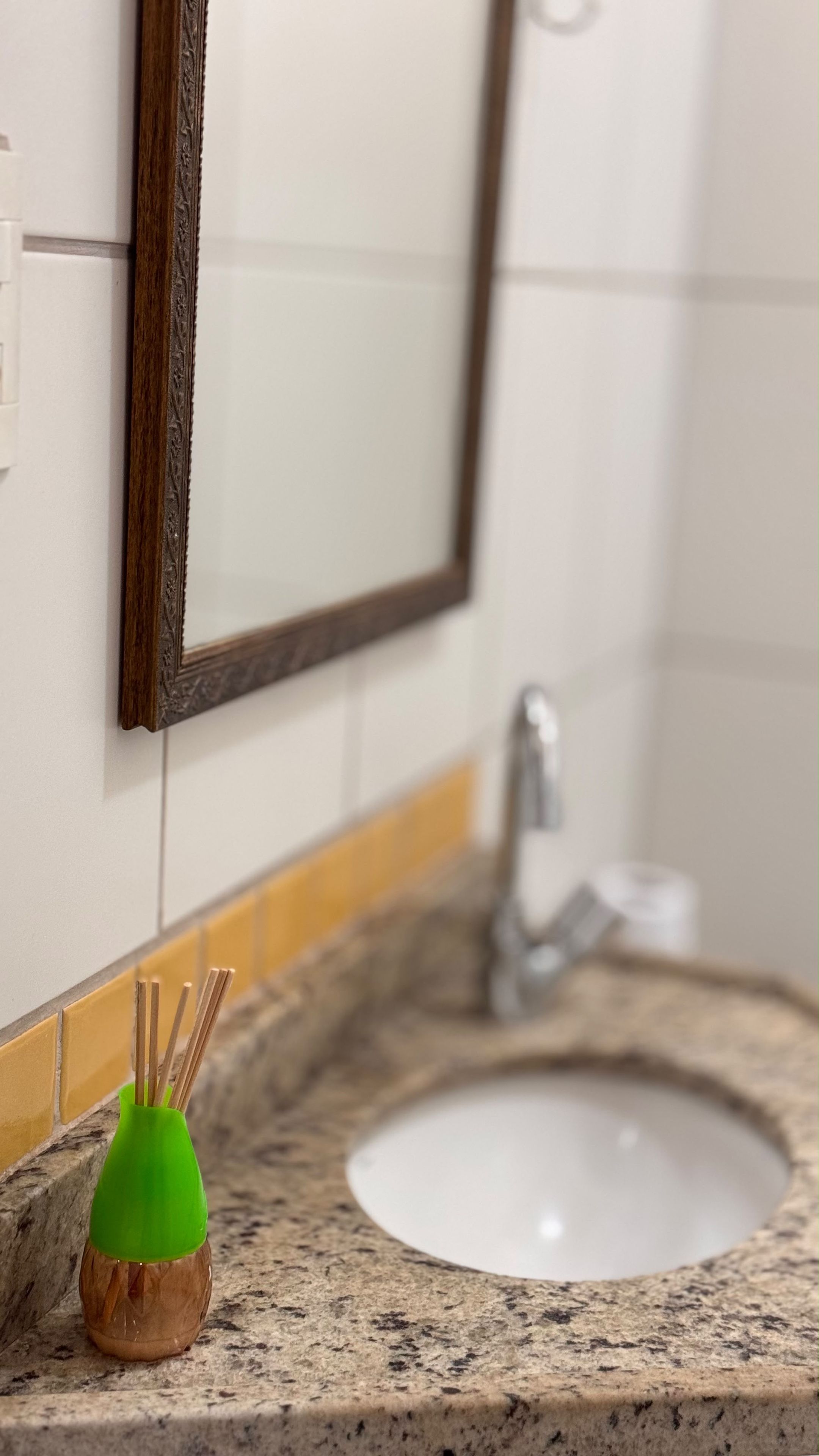 A bathroom with a sink, mirror, and a green candle holder on the countertop.