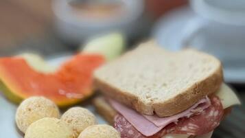 Une assiette contenant un sandwich, une tranche de pastèque et quelques pâtisseries rondes, le tout posé sur une table.