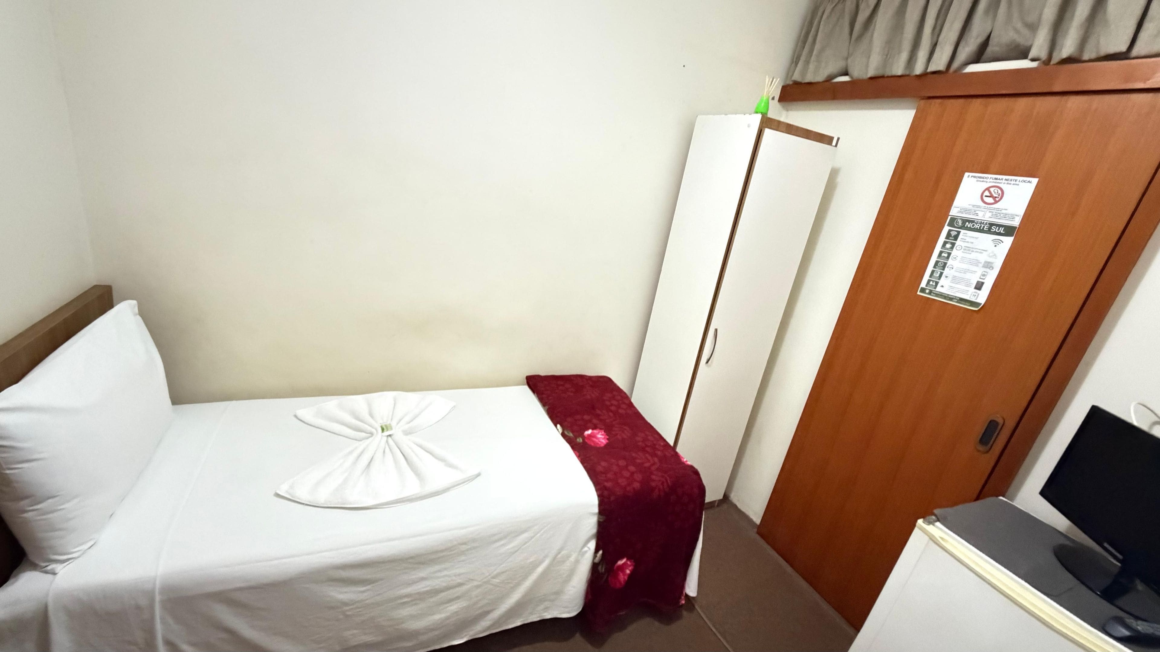 A hotel room with a bed, a wardrobe, and a desk with a computer.