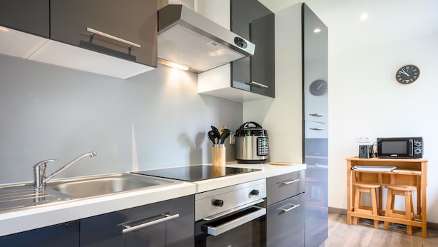 Een moderne keuken met roestvrijstalen apparatuur, een inbouwoven en een magnetron op een houten tafel.