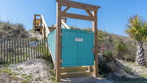 Une structure en bois avec une porte turquoise, une enseigne indiquant « Toppeel Villas », et un panneau d’avertissement concernant une surveillance vidéo de 4 heures.