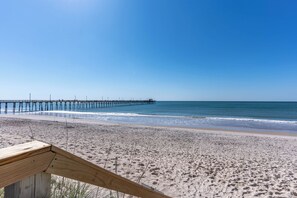 A beach with a wooden pier extending into the water.