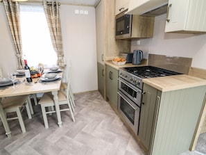 A compact kitchen with a stove, oven, microwave, and a small countertop. - Hedgehog Lodge (Carnforth)
