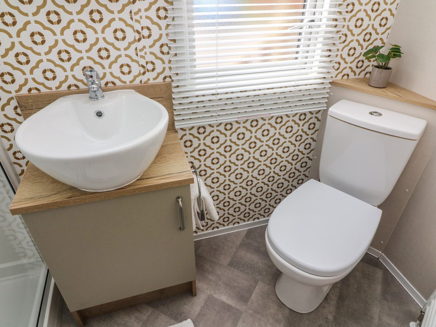 A bathroom with a sink, toilet, and patterned wallpaper.