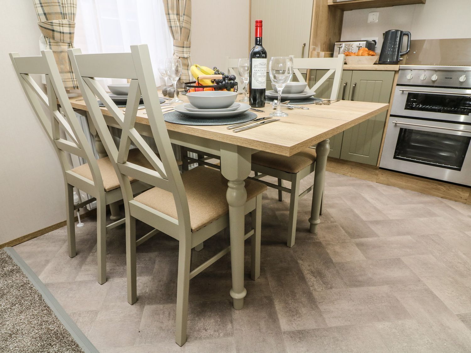Comedor con una mesa de madera, sillas y una cocina al fondo.