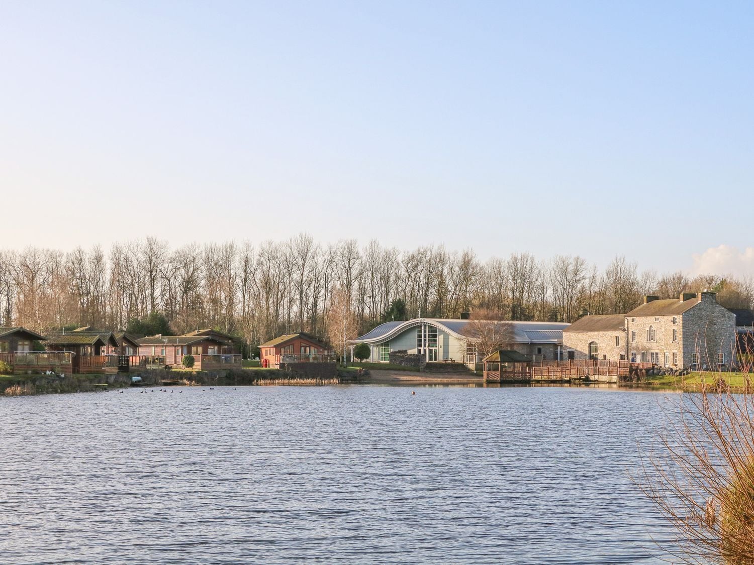Una propiedad frente al lago con varias cabañas, un edificio de piedra grande y un muelle.