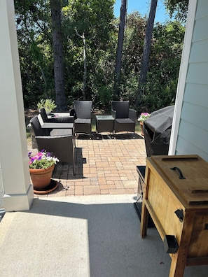 Un espace patio aménagé avec du mobilier d’extérieur, un barbecue et un buffet en bois.