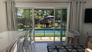 Habitación moderna con puerta de vidrio que da a una zona de piscina, una silla blanca y una alfombra estampada.