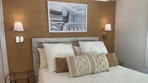 Un dormitorio con una cama, dos lámparas de pared, un cuadro enmarco y una mesita de noche.