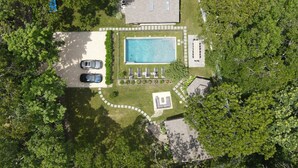 Vue aérienne d’une propriété résidentielle dotée d’une piscine, de deux voitures et d’un espace patio.
