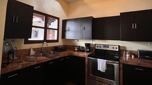 A modern kitchen with dark cabinetry, a built-in oven, and a unique wooden ceiling design. - Casa Don Pancho (Ciudad Vieja)